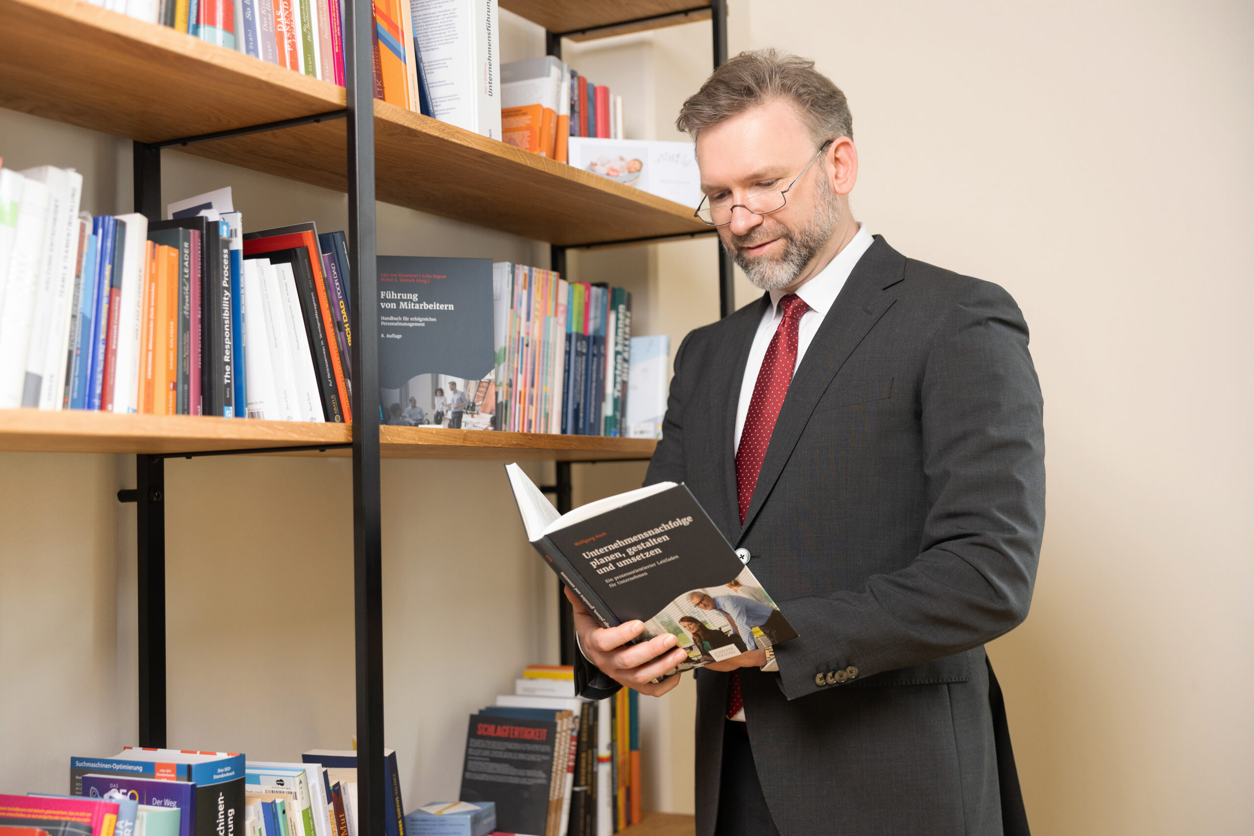 Gesch&auml;ftsf&uuml;hrer Matthias Wolf steht in der Bibliothek des B&uuml;ros der Goldpfad GmbH in Bautzen und liest ein Buch zum Thema Unternehmensnachfolge